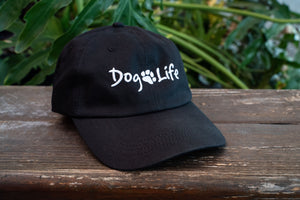 Black Dog Life hat on a wooden table with a plant in the background 