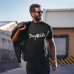 Young black man standing in front of building.  He is wearing sunglasses, has a leather jacket slung over his right shoulder, and he is wearing a Dog Life tee shirt