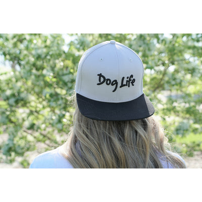 Woman wearing snap back Dog Life hat backwards.