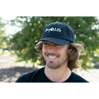 Smiling young man outside with tree in the background wearing Dog Life baseball cap.  Dog Life Dad Hat for sale.